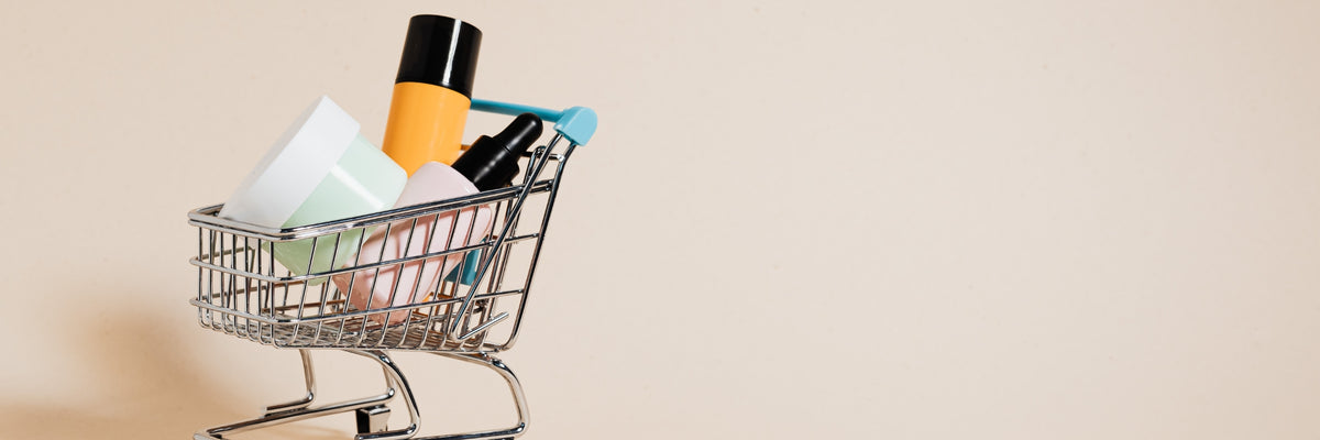 Un petit caddie chromé rempli de flacons de cosmétiques sur un fond beige